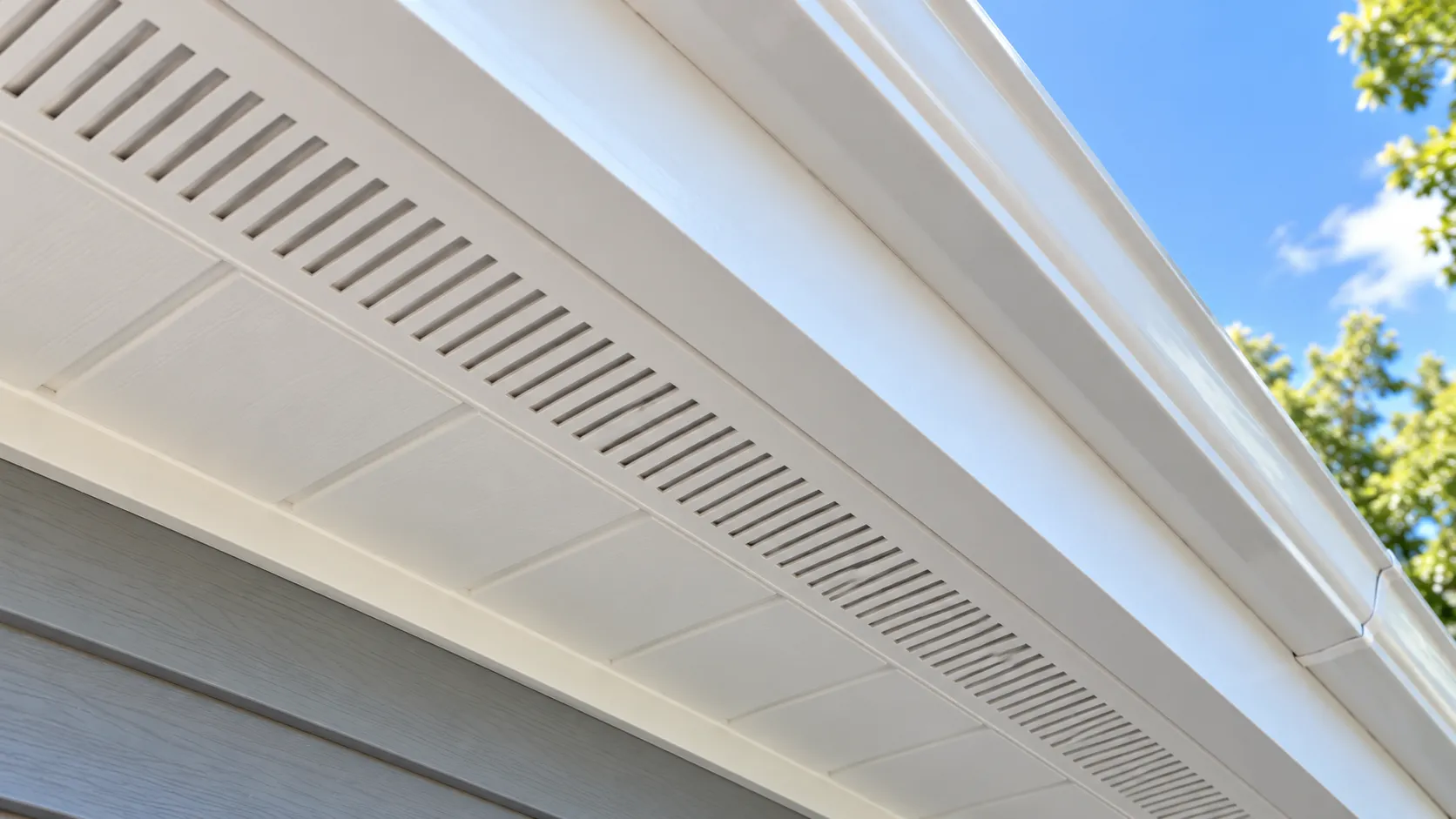 Close-up looking up at a freshly painted white vented soffit, with the vent slots clean and open rather than clogged with paint